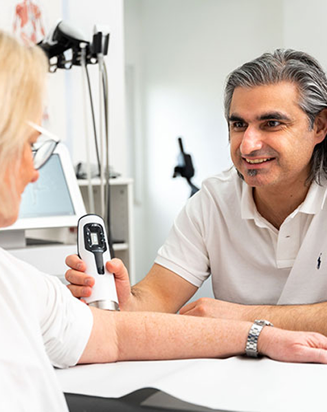 Dr. Bilgic befindet sich im Gespräch mit einer Patientin und analysiert ihre Gelenke.